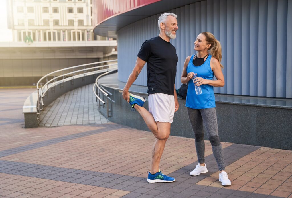 Full length shot of happy middle aged couple, man and woman in sportswear smiling, standing